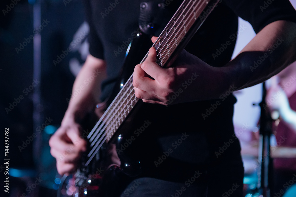 Rock music background, bass guitar player, closeup photo with soft selective focus Rock music background, bass guitar player, closeup photo with soft selective focus