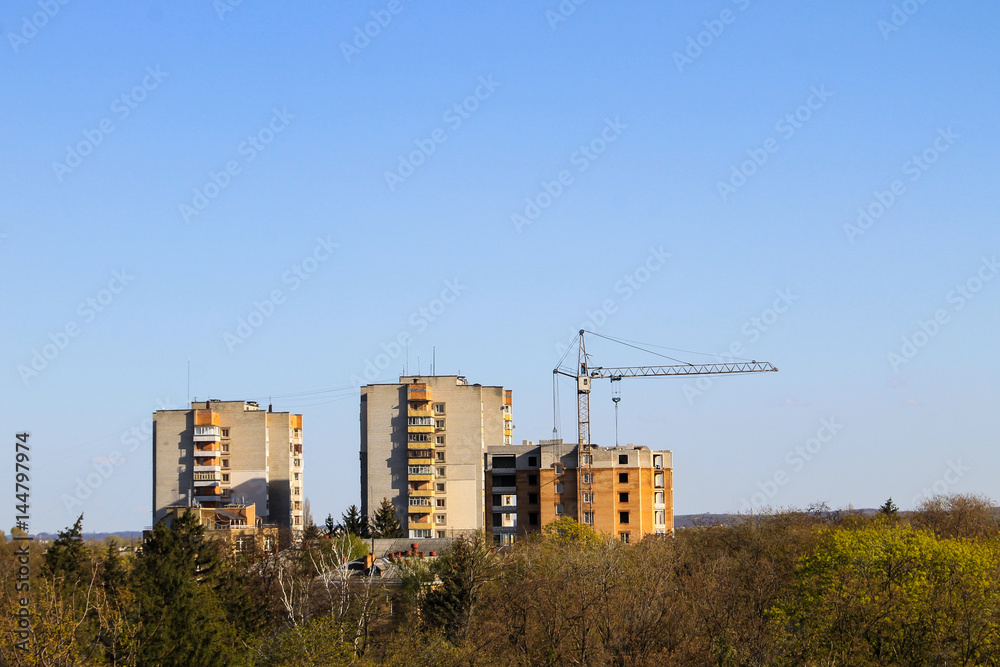 Building crane and building under construction against blue sky Building crane and building under construction against blue sky