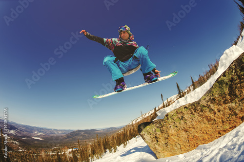 Snowboarder jumping from the springboard against the sky