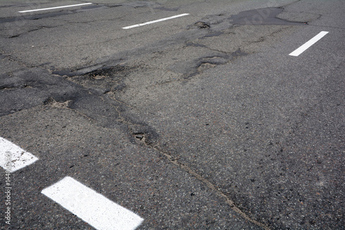 Poor quality of road repair work. Damaged asphalt road, bad road. 