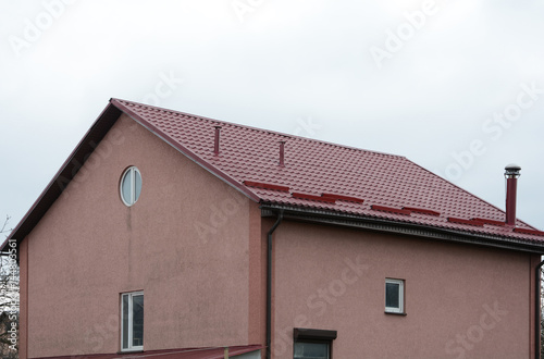 Metal roofing construction. Rain gutter and snow guard. Chimney coaxial. House with individual heating.
