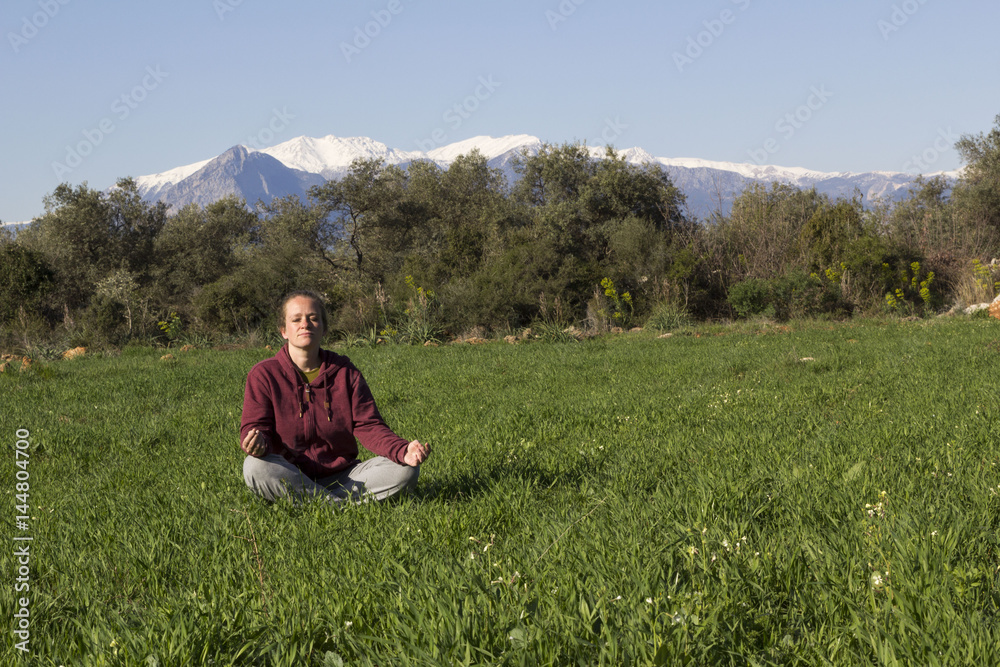 woman sitting in meditation position on grass
