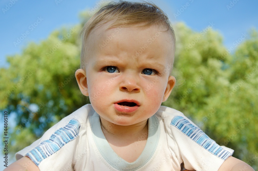 Portrait of thoughtful,surprised and astonishment baby . In the background blue sky and green tree. Child concept. Portrait of thoughtful,surprised and astonishment baby . In the background blue sky and green tree. Child concept.