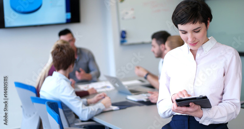 Portrait of  smiling casual businesswoman using tablet  with coworkers standing in background