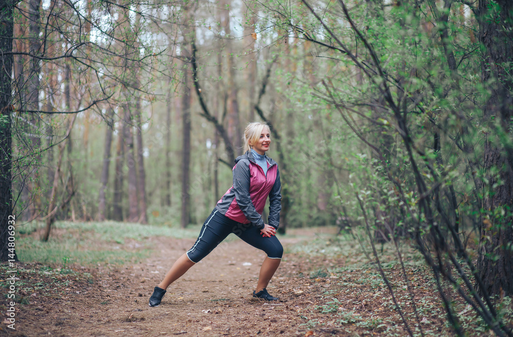 young beautiful girl doing workout in the woods. Blonde girl tracksuit doing exercises young beautiful girl doing workout in the woods. Blonde girl tracksuit doing exercises