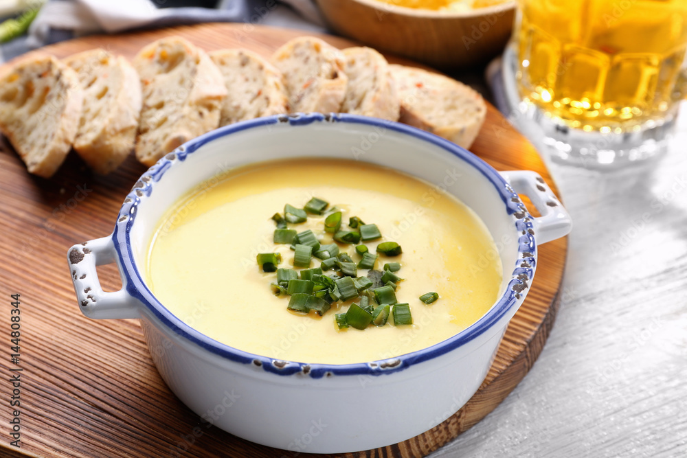 Bowl with beer cheese dip and slices of bread on wooden board