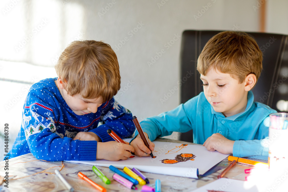 Two little kid boys at school painting a story with colorful pens Two little kid boys at school painting a story with colorful pens