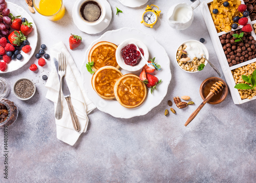 Healthy breakfast background with coffee, pancakes, fresh berries, quick cereals and orange juice, copy space, top view.