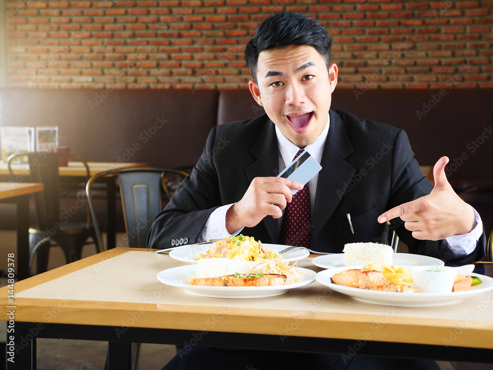 Man in suit cheerfully smiling, holding credit card and looking at camera. Man in suit cheerfully smiling, holding credit card and looking at camera.
