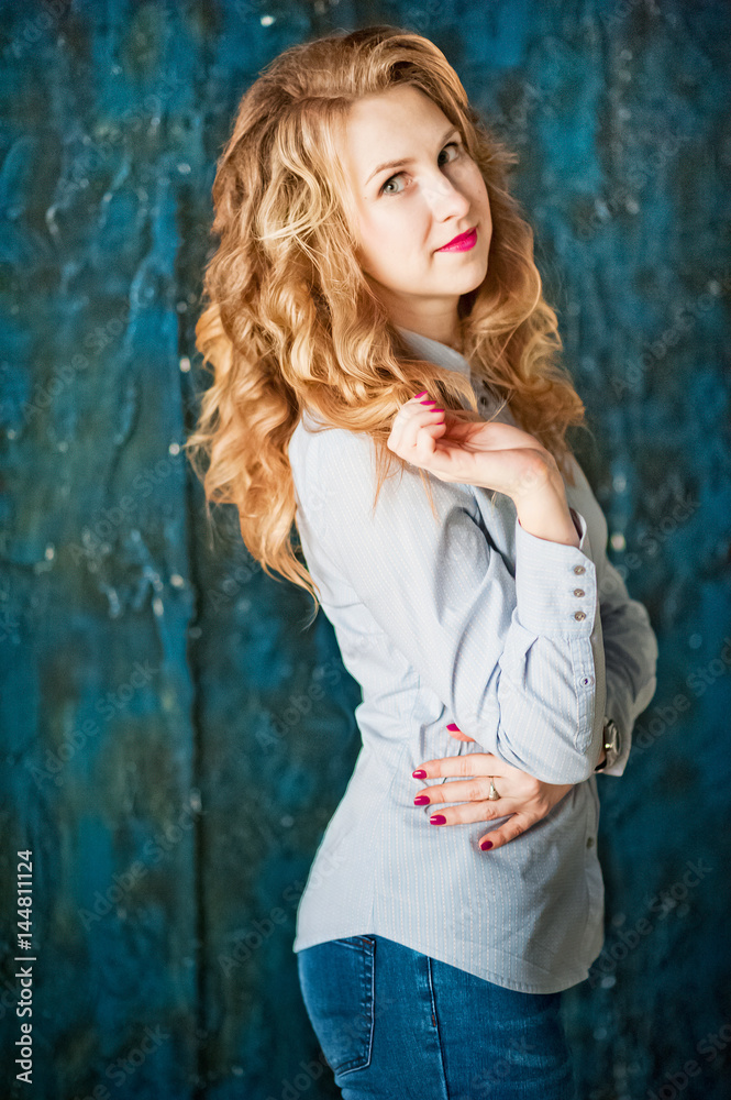 Fototapeta premium A beautiful girl in a blue shirt with spring flowers. Girl with beautiful blond curls
