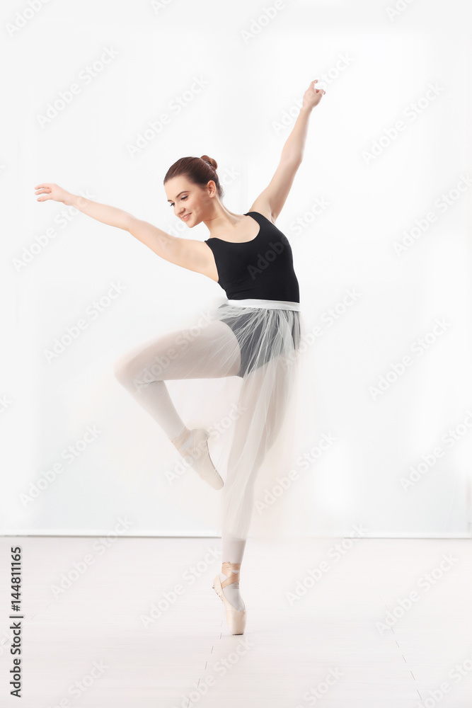 Fototapeta premium Ballet art concept. Young beautiful ballerina training in dance hall
