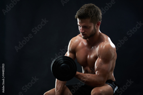 Studio shot of a fit muscular young man exercising with dumbbell shirtless on black background copyspace fitness gym sport sportsman athlete sexy hot body care health motivation effort achievement. © serhiibobyk