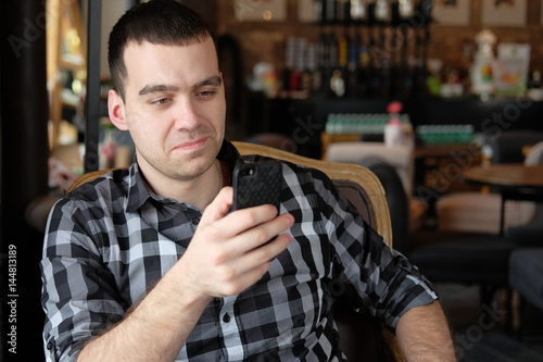 A successful young man in a dark plaid shirt in the cafe does business. Young hipster holding a smartphone. Office worker on lunch talking on the phone. business meeting. send a message.