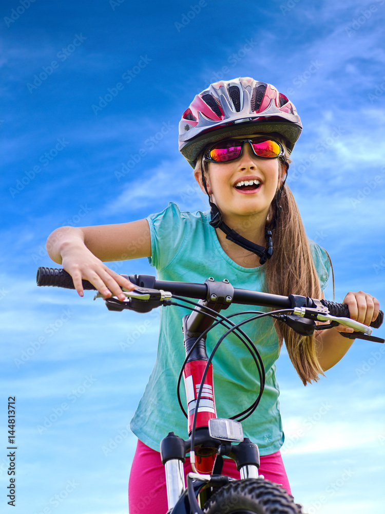 Kid traveling bicycle in summer park. Child in helmet road bike for running on green grass aganist blue sky with white clouds. Kid traveling bicycle in summer park. Child in helmet road bike for running on green grass aganist blue sky with white clouds.