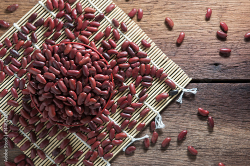 Red beans in a cup with a wooden sign on the wooden floor.