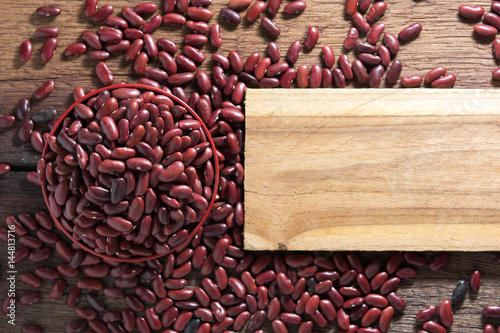 Red beans in a cup with a wooden sign on the wooden floor.