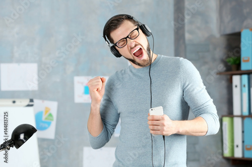 Handsome man listening to m...