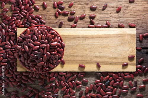 Red beans in a cup with a wooden sign on the wooden floor.