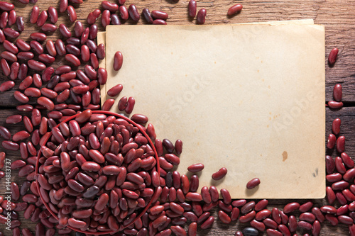 Red beans in a cup with a wooden sign on the wooden floor.