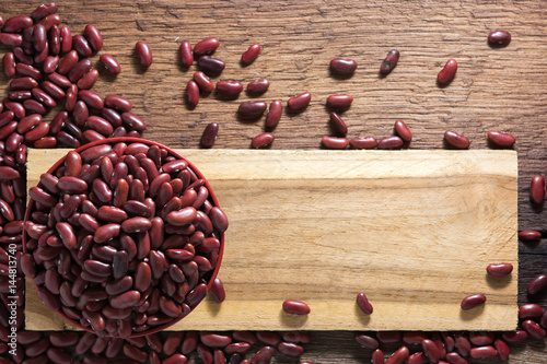 Red beans in a cup with a wooden sign on the wooden floor.