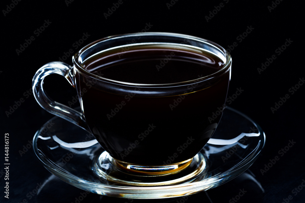 Hot black coffee smokes in a glass cup on a black background, studio light Hot black coffee smokes in a glass cup on a black background, studio light