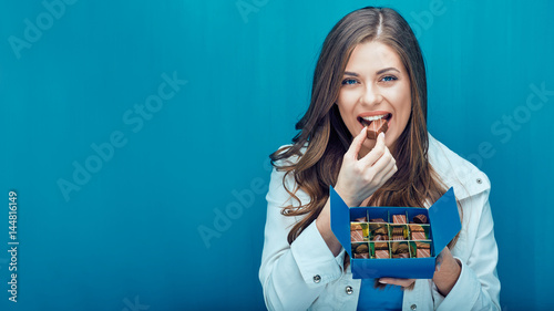 Happy young woman eating chocolate candies.