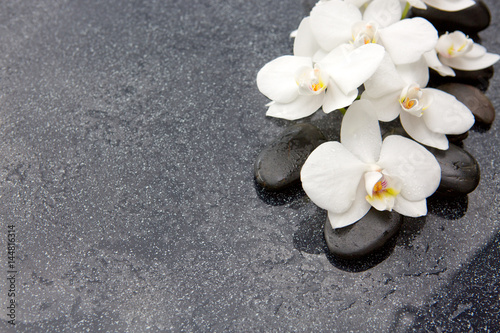 Spa stones and white orchid on grey background.