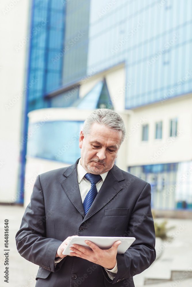 successful businessman with digital tablet on background of office building successful businessman with digital tablet on background of office building