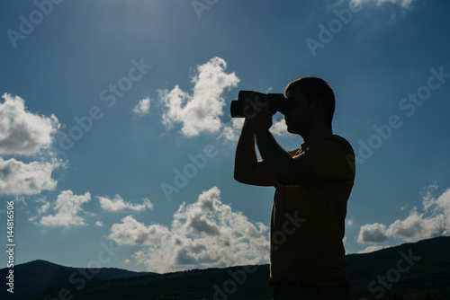 Man with binocular, sky and clouds