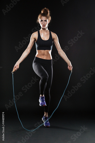 Full length image of fitness woman jumping with jumping-rope