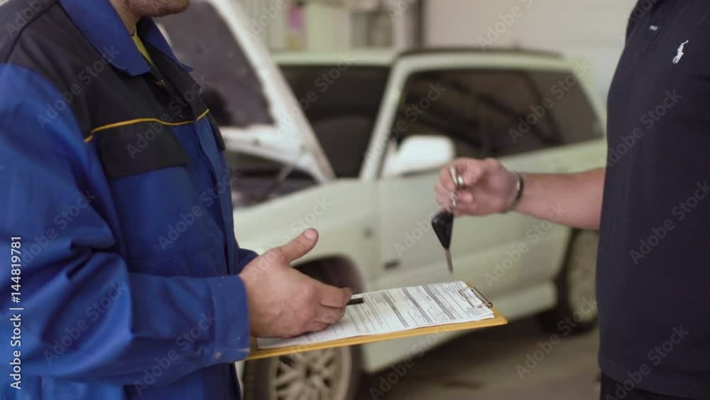 Close up of a hands of car mechanic taking car keys and shaking hads with client