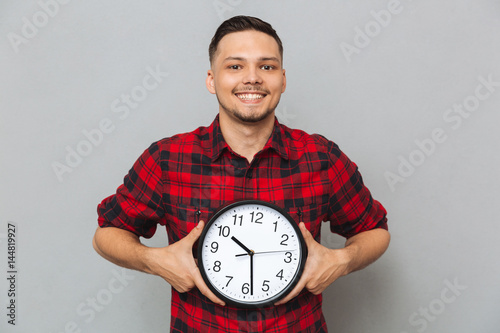 Smiling man holding clock in hands