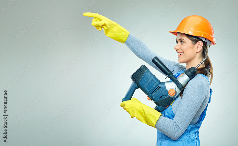 Smiling woman builder with building tool pointinf finger on copy space. Smiling woman builder with building tool pointinf finger on copy space.