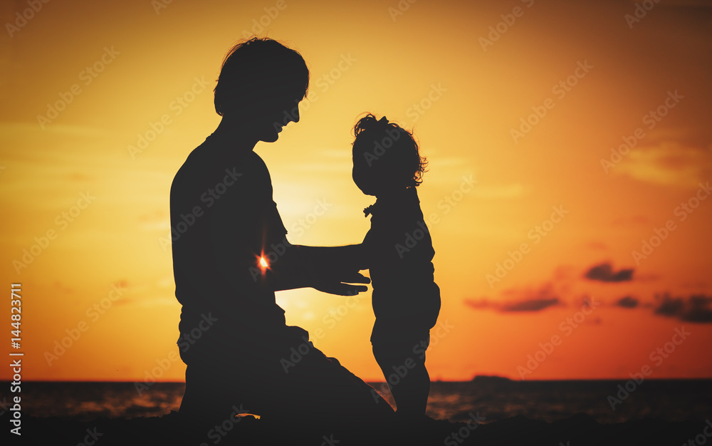 Silhouette of father and daughter on sunset beach