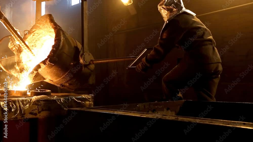 Worker controlling metal melting in furnaces. Workers operates at the metallurgical plant. The liquid metal is poured into molds.
