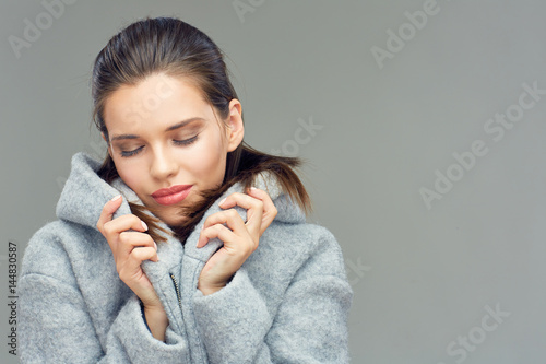 Young beauty with closed eyes touching coat collar