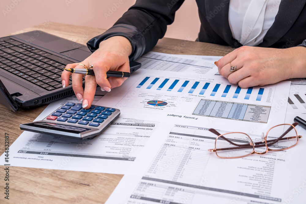 Business woman account annual budget with laptop, pen and graph. Business woman account annual budget with laptop, pen and graph.
