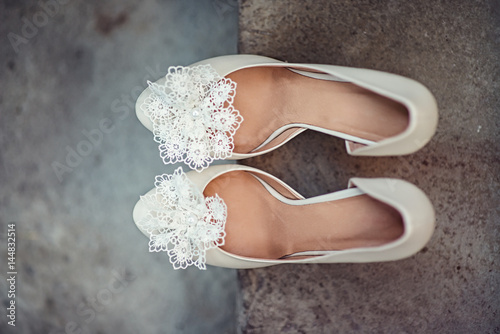 Luxury ivory wedding shoes with lace flower on it, for bride, selective focus. photo
