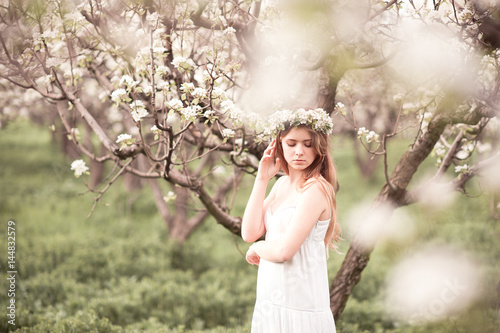 Young beautiful teen girl 14-16 year old posing in apple orchard. Wearing white elegant dress. Summer time.