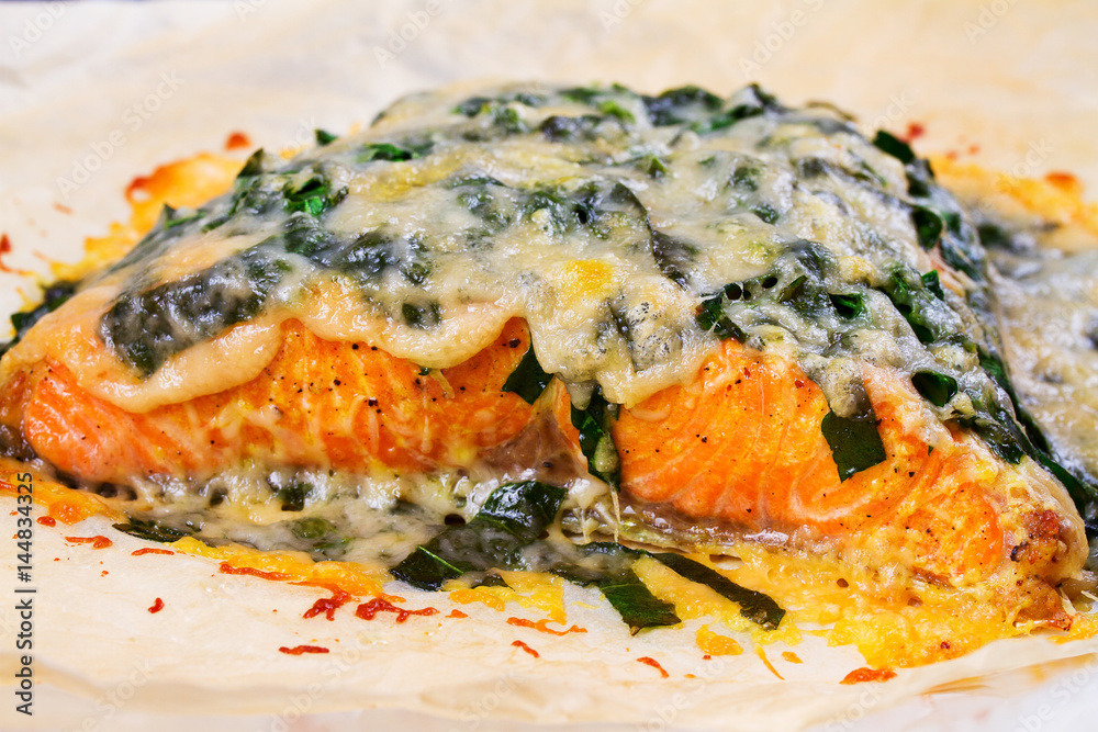 Salmon with spinach and cheese. Baked fish on parchment