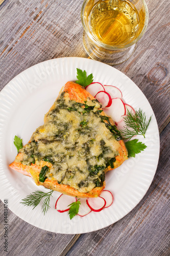 Baked salmon with spinach and cheese. Fish on white plate.