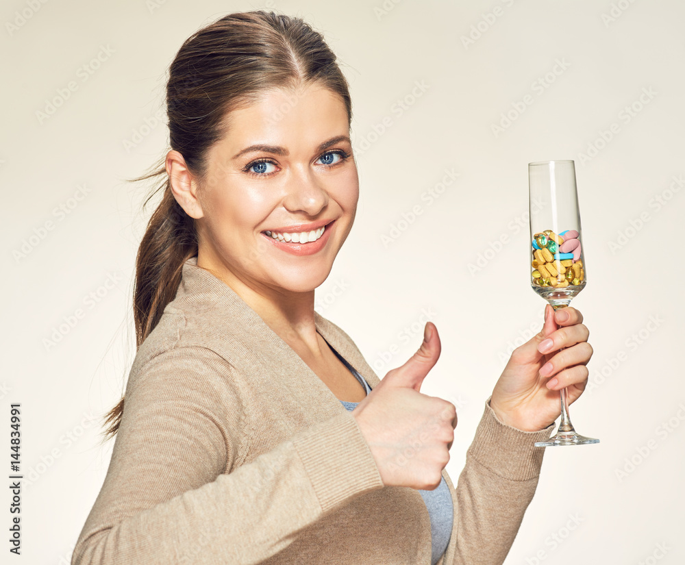Smiling woman holding glass with vitamin pills. Smiling woman holding glass with vitamin pills.