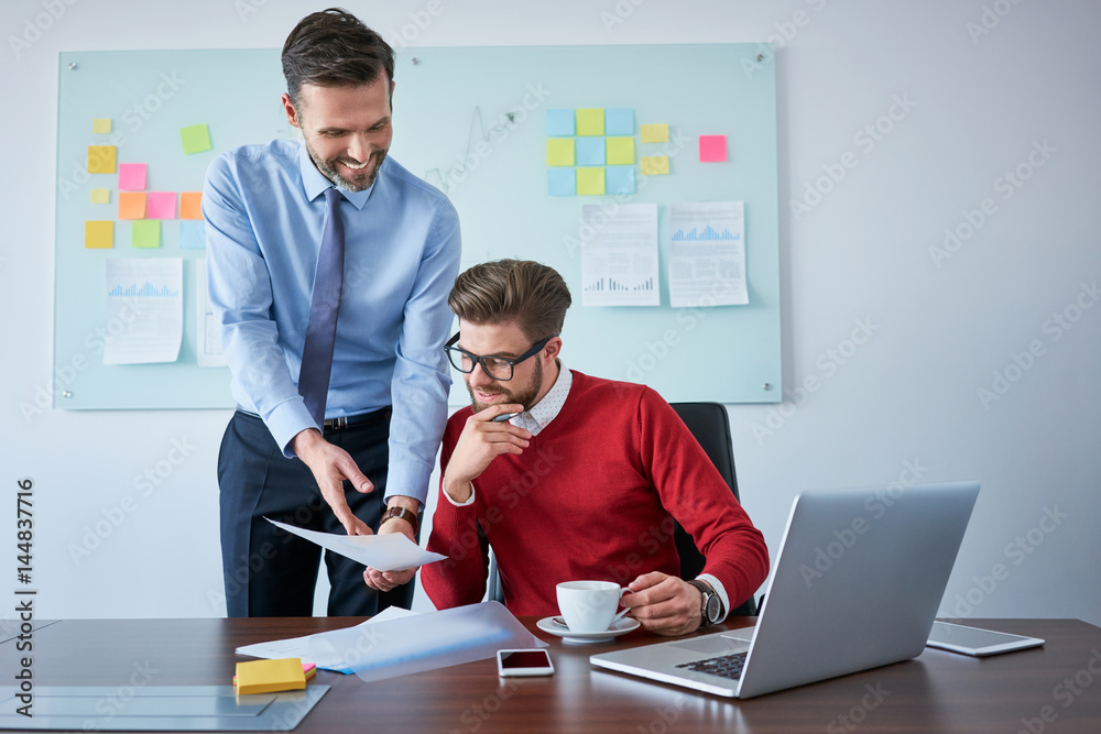 Two business partners reading contract document at office Two business partners reading contract document at office