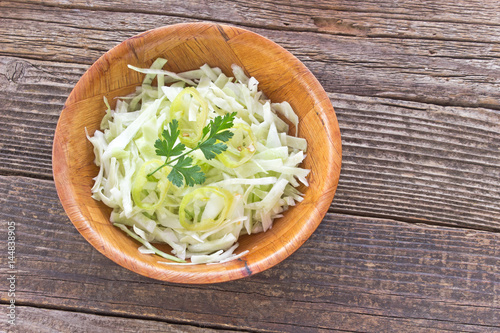 Sliced young cabbage salad in bamboo bowl on table