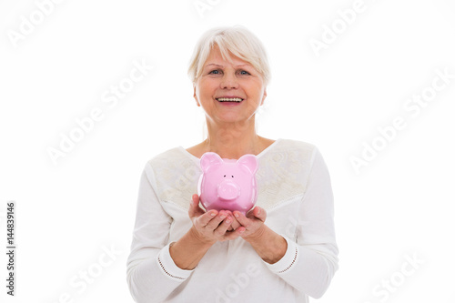 Senior woman holding piggy bank   © pikselstock