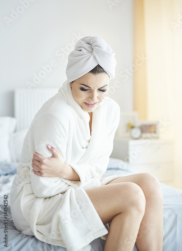 Woman holding her belly in bedroom .