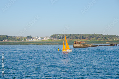 Lorient harbor, orange sailboat which leaves the port, Brittany 