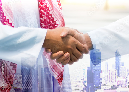 Arab businessman are shaking hand on city background, Business Successful concept, double exposure.