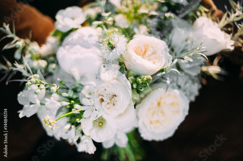 a beautiful bridesmaid bouquet of white flowers lying on a brown easy chair