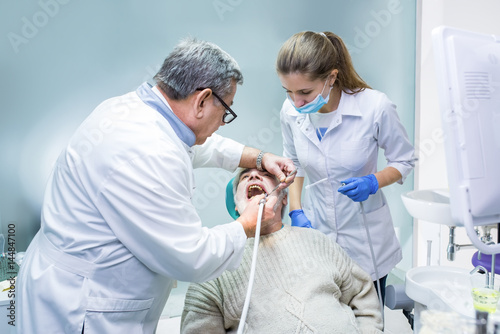 Dentist and assistant working. Elderly dental patient. Get help from qualified professionals.